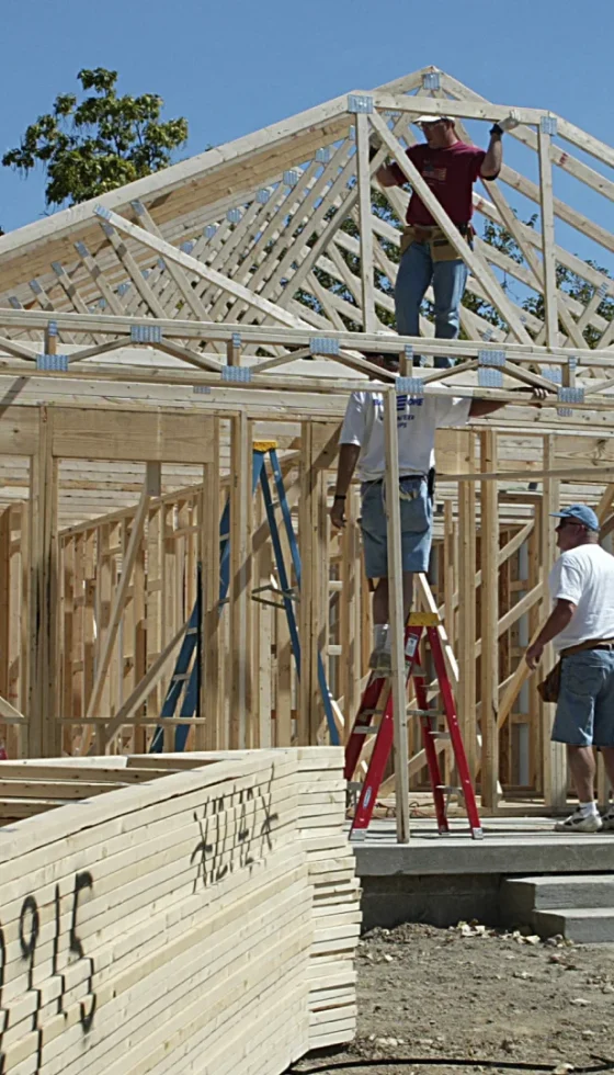 Volunteers helping to build new home and stacks of lumber out front