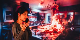 Woman calls for help as a kitchen fire spreads behind her, showing one of the most serious causes of house fires.