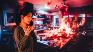 Woman calls for help as a kitchen fire spreads behind her, showing one of the most serious causes of house fires.