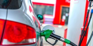 A car refuels at a gas station pump, representing everyday strategies drivers use to find cheap gas and save money at the pump.