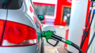 A car refuels at a gas station pump, representing everyday strategies drivers use to find cheap gas and save money at the pump.