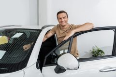 Man standing next to a new car, illustrating insurance coverages for a new car and vehicle protection