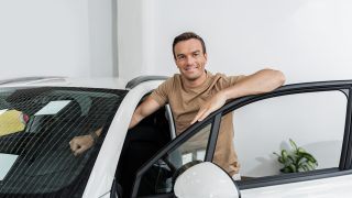 Man standing next to a new car, illustrating insurance coverages for a new car and vehicle protection