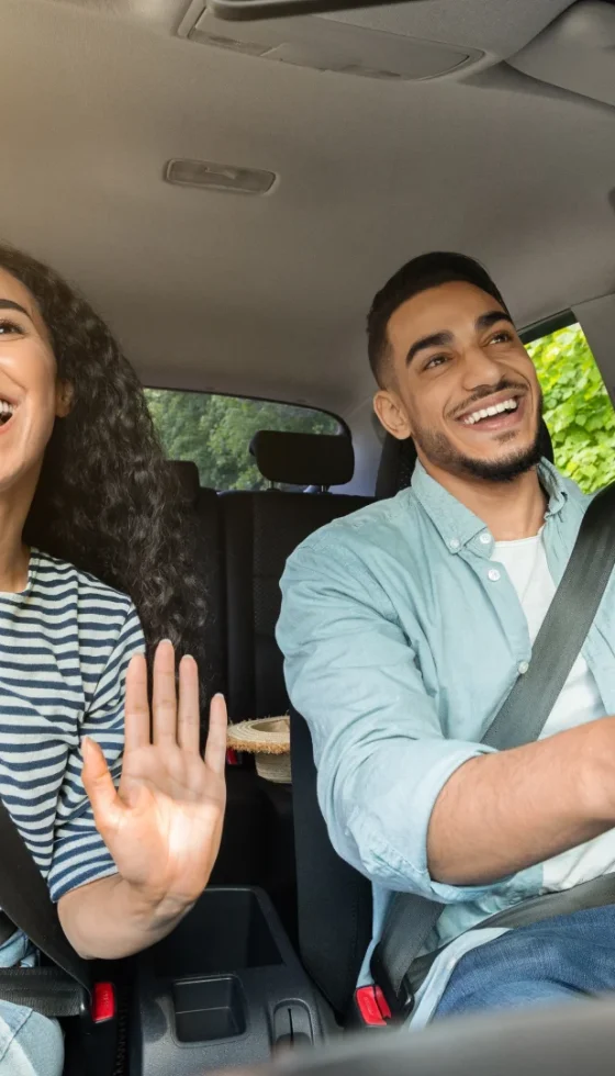 Smiling millennial couple having fun while driving their car on a road trip