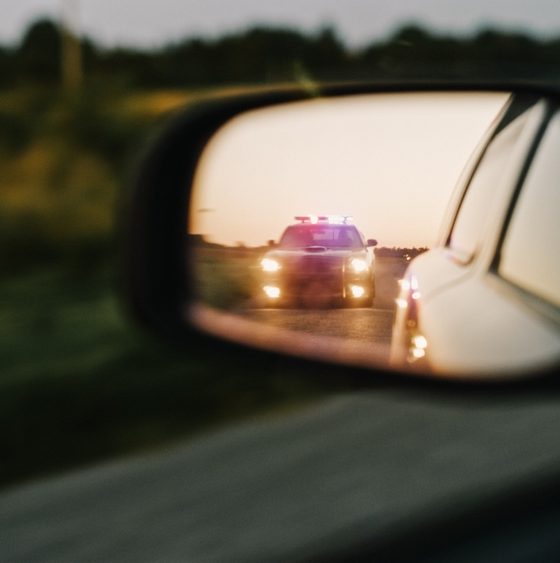 Police vehicle visible in a driver's side mirror during a traffic stop after receiving a speeding ticket.