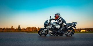 Motorcyclist riding a sport motorcycle on an open road at sunset, representing motorcycle insurance and rider safety.