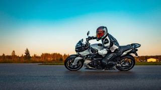 Motorcyclist riding a sport motorcycle on an open road at sunset, representing motorcycle insurance and rider safety.