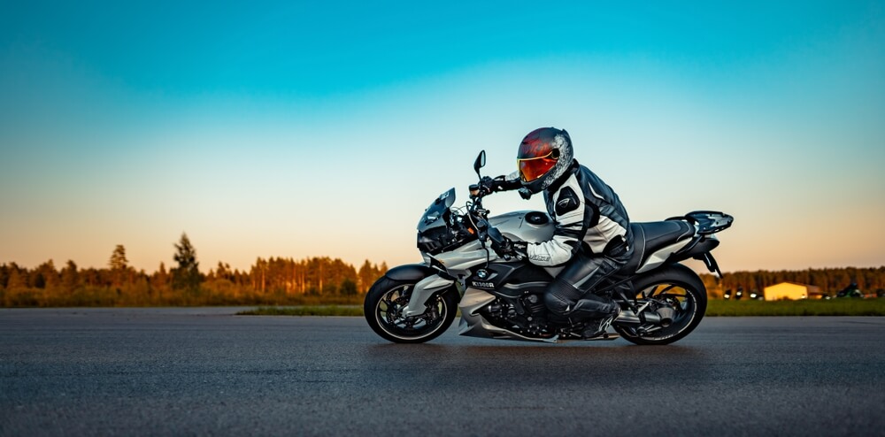 Motorcyclist riding a sport motorcycle on an open road at sunset, representing motorcycle insurance and rider safety.