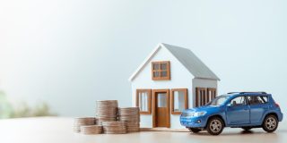 House and car models with coins representing bundling auto and home insurance.