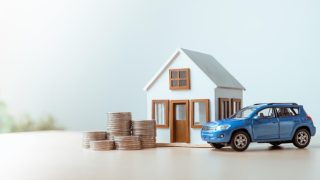 House and car models with coins representing bundling auto and home insurance.