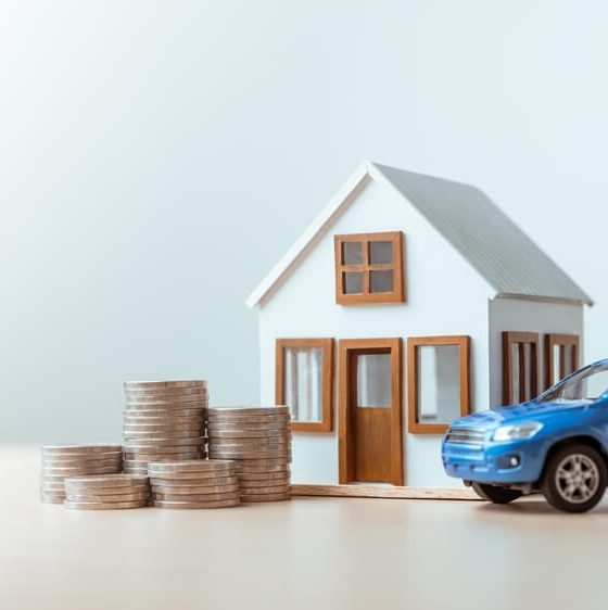 House and car models with coins representing bundling auto and home insurance.