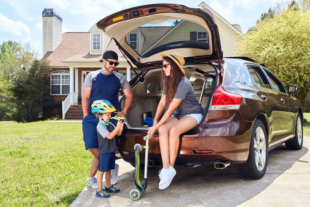 Family with their car outside their home representing bundled auto and home insurance coverage.