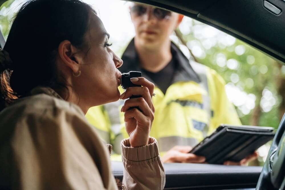 Driver taking a roadside breathalyzer test during a traffic stop, representing the consequences and recovery process in life after a DUI.