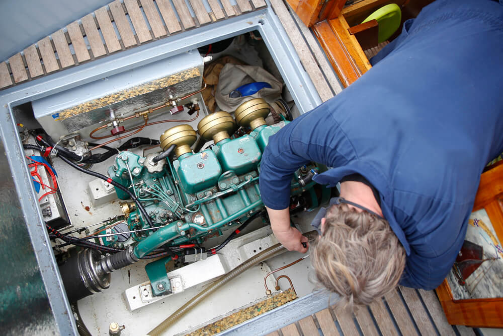 A mechanic adjusts the engine of a boat - cheap boat insurance.