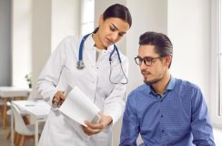 Female doctor showing test results to male patient in medical clinic. General practitioner consulting male client at medical checkup visit in hospital. Medicine and healthcare concept, free or low-cost health insurance in California.