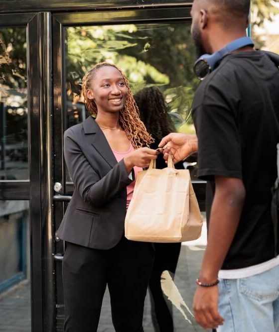 Office food delivery service courier giving customer order package. Man holding restaurant takeaway meal, happy cheerful company employee taking lunch paper bag, car insurance for delivery drivers.