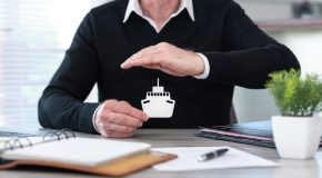 Insurer protecting a paper boat with his hand, concept of boat insurance.