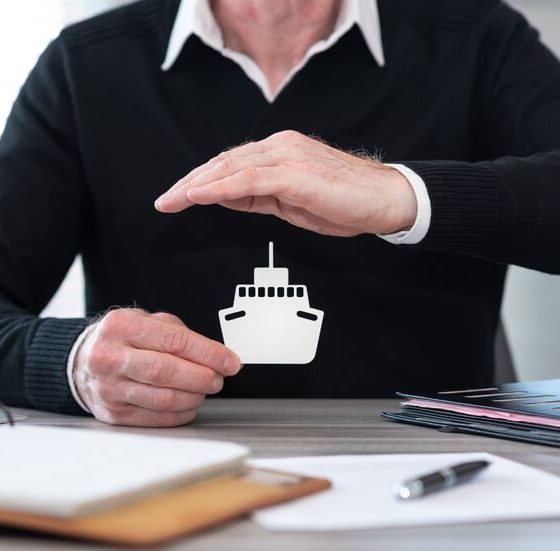 Insurer protecting a paper boat with his hand, concept of boat insurance.