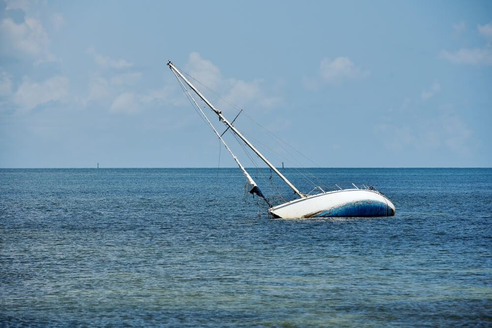 A sailboat runs aground and sinks in the shallow waters around Key West, cheap boat insurance.