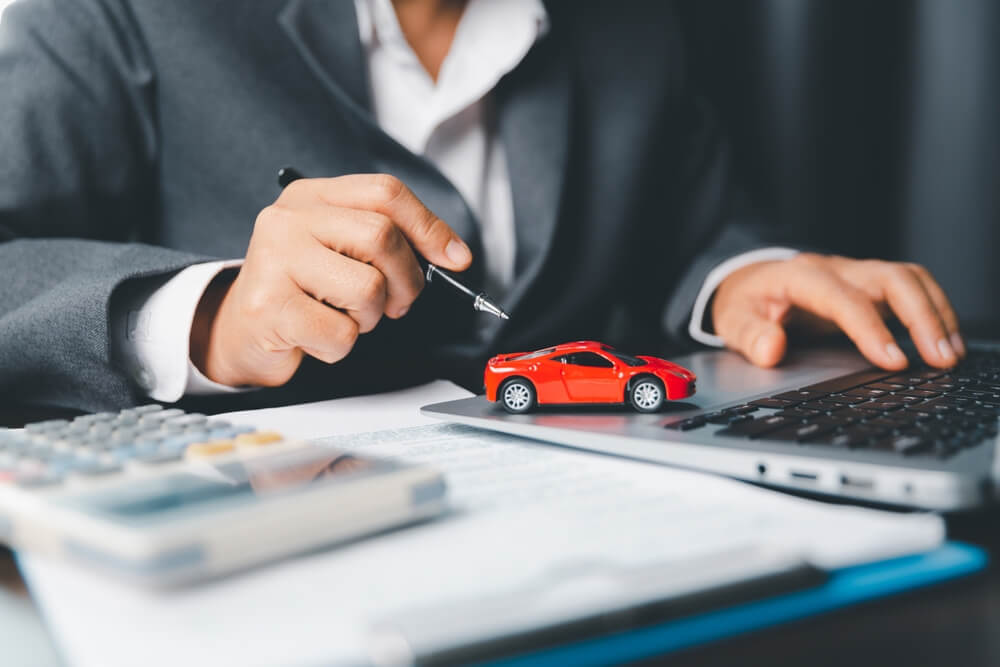 Car dealer business woman signing car insurance document wondering How Often Should You Review Your Car Insurance
