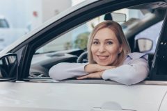 Woman sitting in a new automobile wondering How Often Should You Review Your Car Insurance