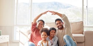 Family, roof and portrait with children in home for protection, love and insurance on floor. Happy, house and mother, father and kids with people hands cover for safety, security and support.