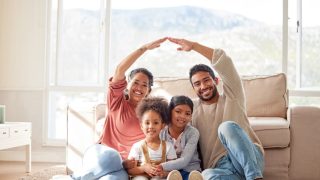 Family, roof and portrait with children in home for protection, love and insurance on floor. Happy, house and mother, father and kids with people hands cover for safety, security and support.