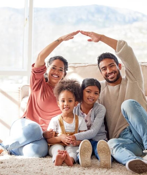 Family, roof and portrait with children in home for protection, love and insurance on floor. Happy, house and mother, father and kids with people hands cover for safety, security and support.