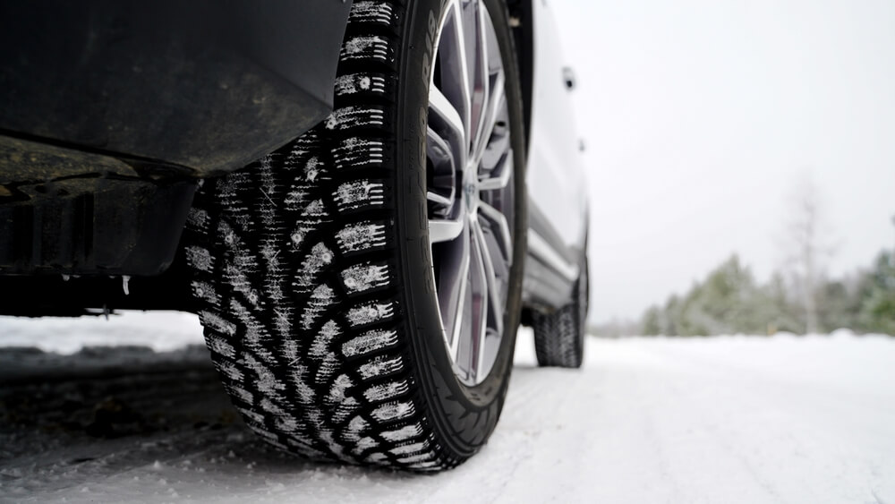 A car tire gripping snowy ground underscores the need for solid car insurance in winter.