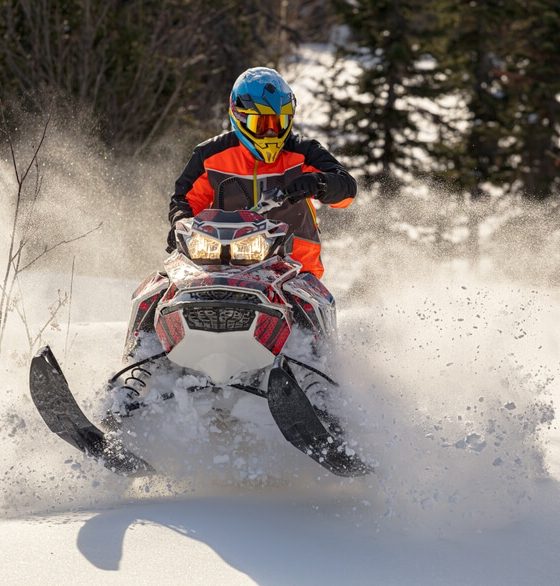 Young man driving a snowmobile in motion on a beautiful winter day, highlighting snowmobile insurance.