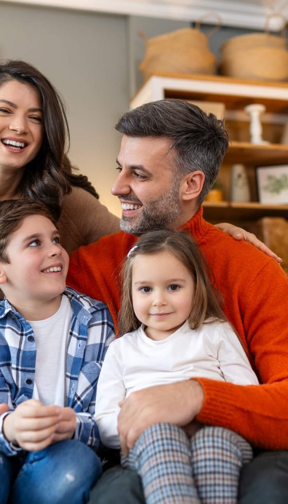 Happy family relaxing on the sofa at home, representing the protection homeowners insurance provides