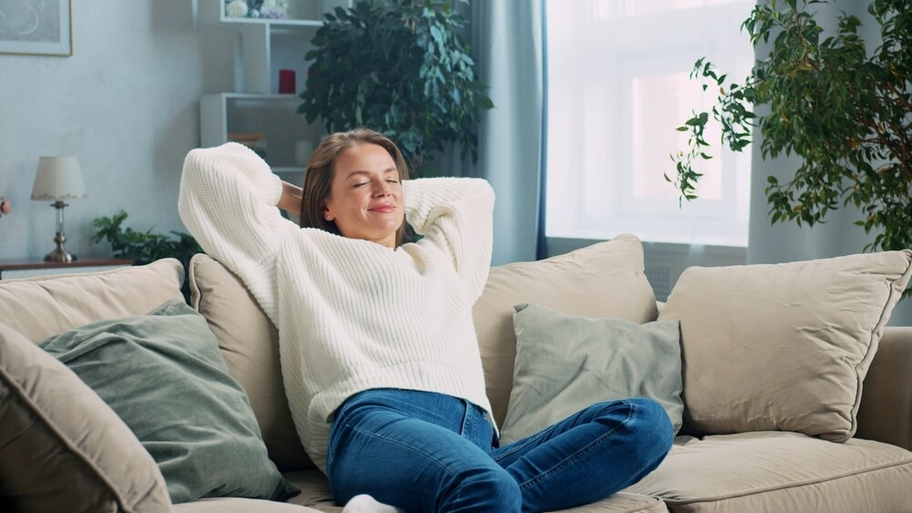 Young woman relaxing at home, enjoying peace of mind with renters insurance.