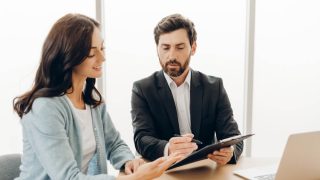 A woman reviewing insurance paperwork with an advisor, reflecting concerns about choosing coverage when the deductible is too high