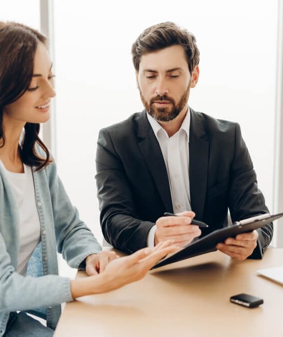 A woman reviewing insurance paperwork with an advisor, reflecting concerns about choosing coverage when the deductible is too high