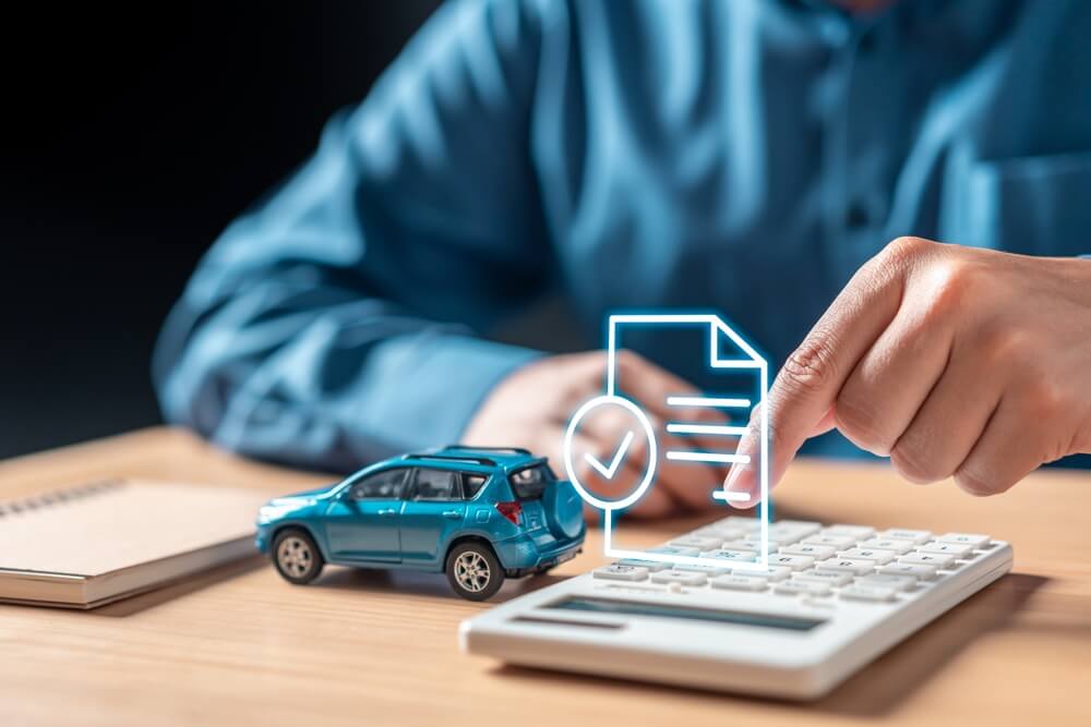 Person calculating auto insurance costs beside a model car, illustrating concerns about a deductible too high for repairs