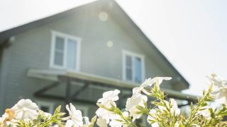House exterior with blooming flowers in spring, symbolizing the right time for a spring home insurance review and policy check.