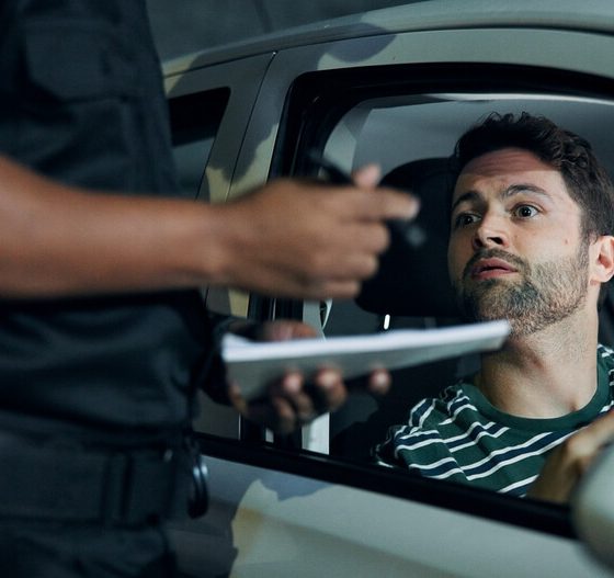 Police officer issues a ticket to a worried driver during a traffic stop, illustrating what happens if insurance lapses.