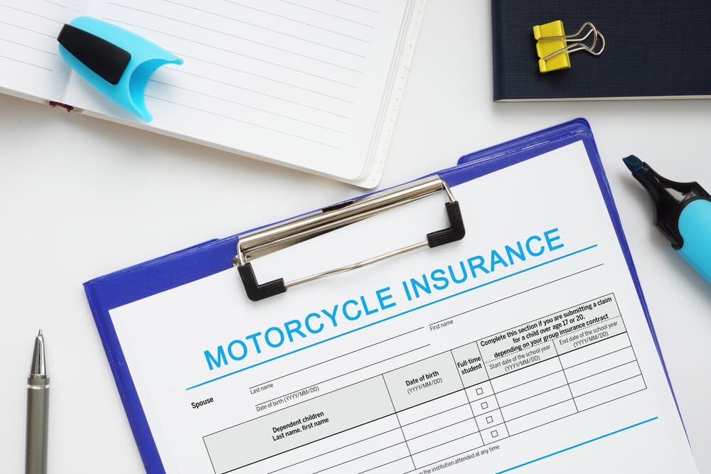 Motorcycle insurance application form on a clipboard surrounded by office supplies, symbolizing affordable coverage and policy planning for riders.