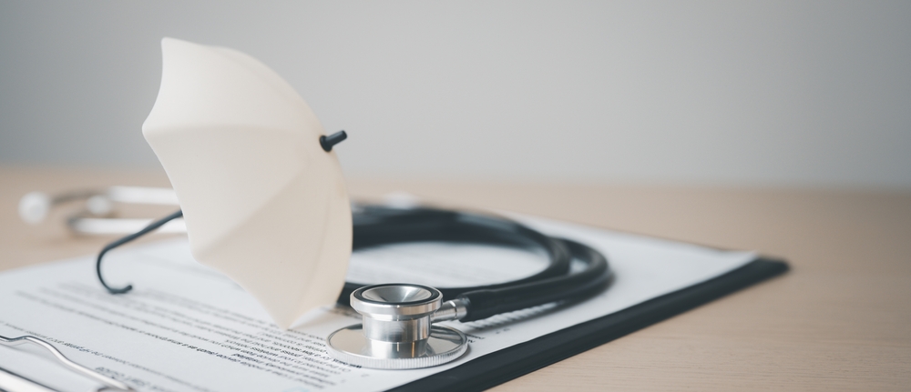 Preventative health care concept with a stethoscope, medical paperwork, and a small umbrella symbolizing health insurance coverage and preventive care.