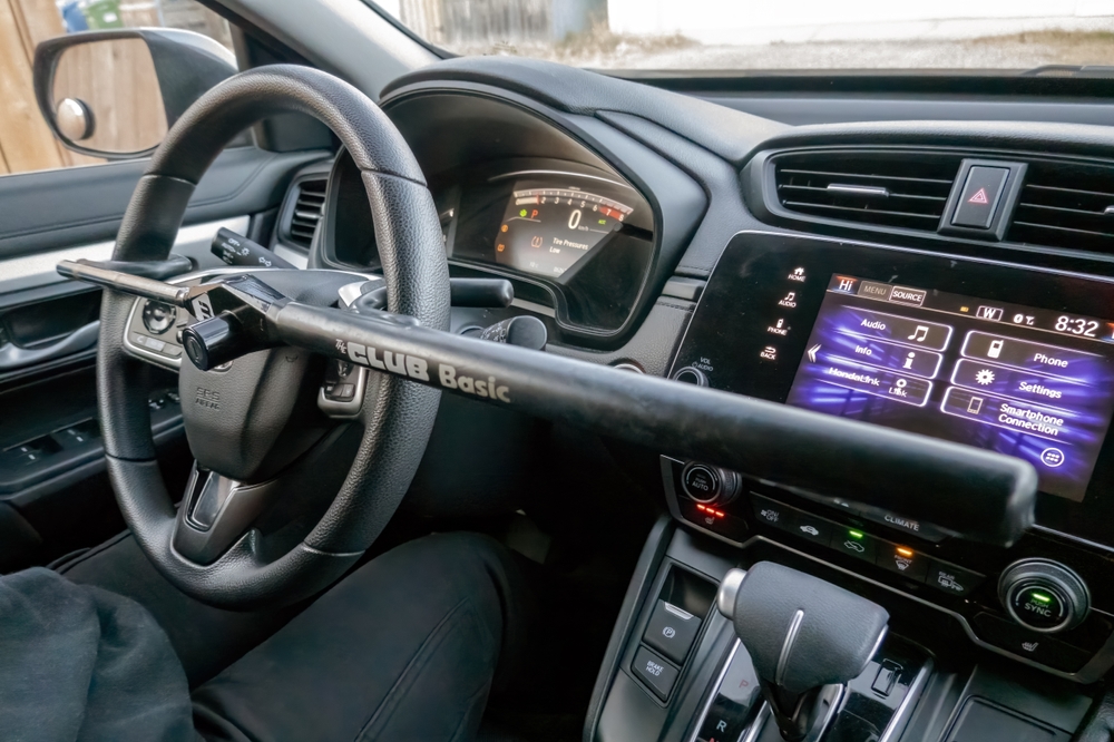 Steering wheel lock installed across the steering wheel inside a parked car, demonstrating a physical anti-theft device used to help deter vehicle theft.