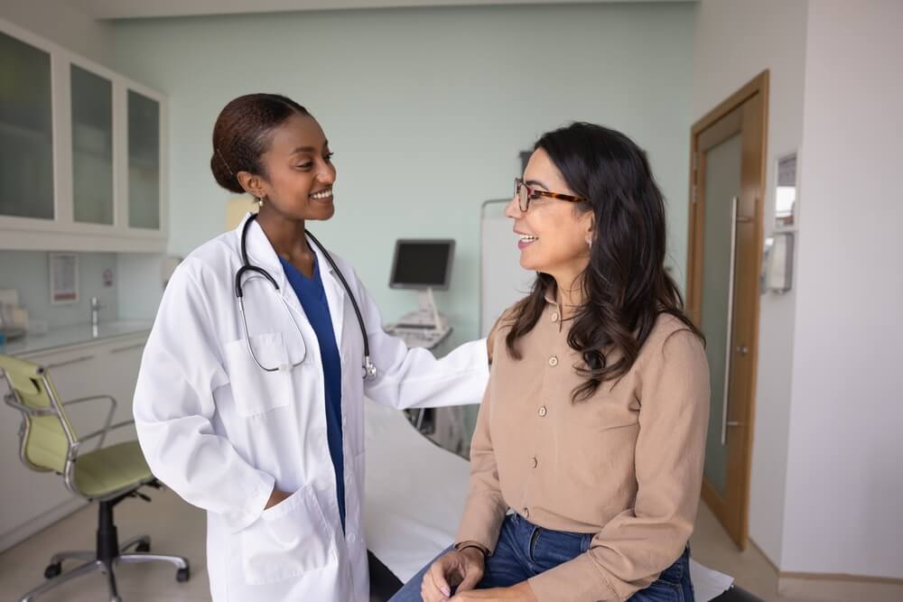 Smiling doctor speaking with a patient in a medical office, highlighting access to healthcare through Covered California health insurance enrollment.