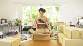 Small business owner packing customer orders while considering home-based business insurance coverage.