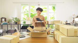 Small business owner packing customer orders while considering home-based business insurance coverage.