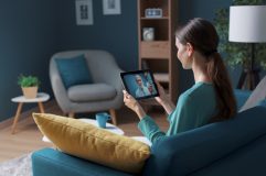 Woman using a tablet for a telemedicine mental health appointment from home.