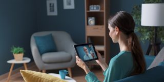 Woman using a tablet for a telemedicine mental health appointment from home.