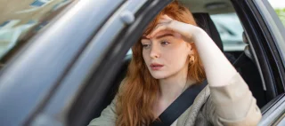 Young woman looking frustrated while driving a car