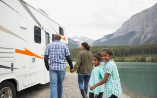 Family at lakeside walking toward RV – cheap RV insurance.