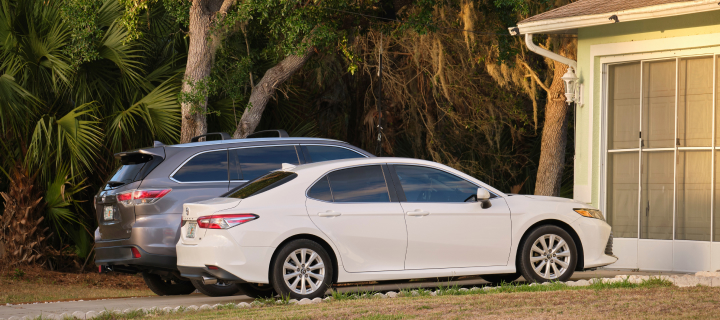 Cars parked in front of wide garage double door on concrete driveway of new modern american house. Sarasota, USA.