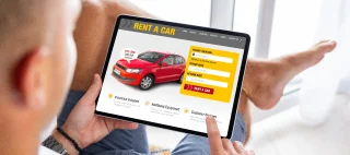 Man viewing car rental website on tablet computer – cheap car insurance.