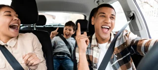 Excited young african american family singing riding new car and having fun enjoying summer road trip on vacation